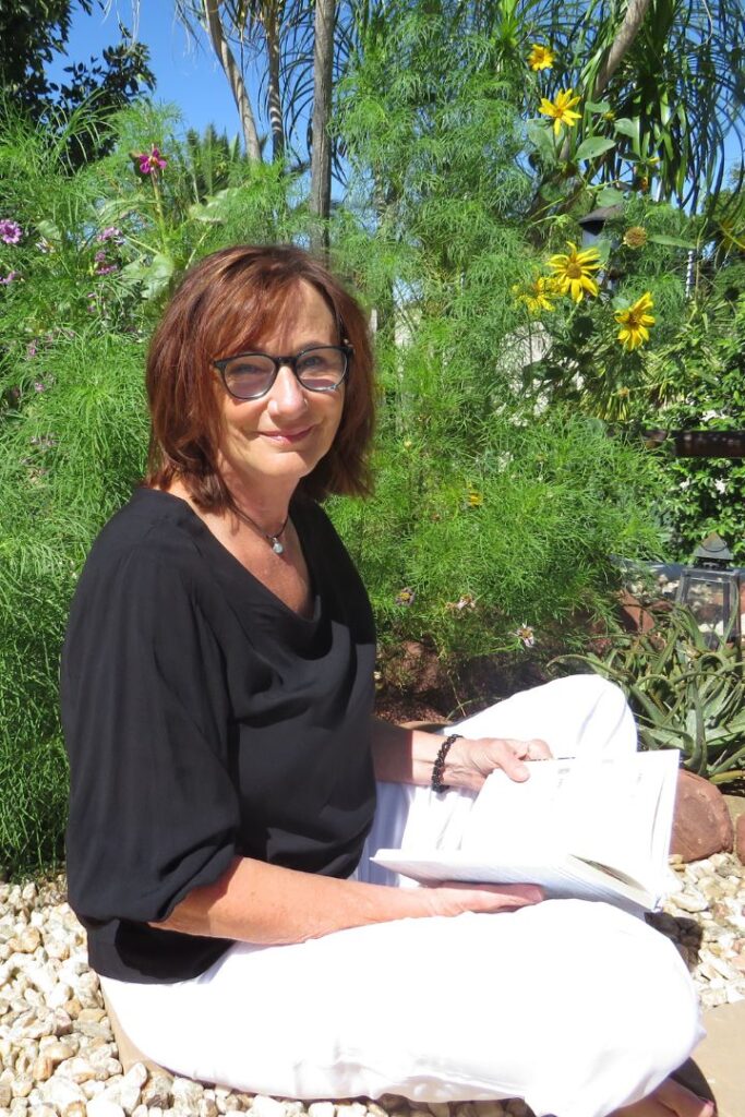 Barbara Erdt sitzt im Schneidersitz im Garten und liest ein Buch. Sie ist Heilpraktikerin in Mengkofen und hat ihr Einzugsgebiet bis Landau an der Isar.